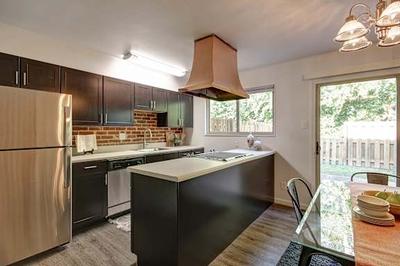 A kitchen with a black counter and a stainless steel refrigerator.
