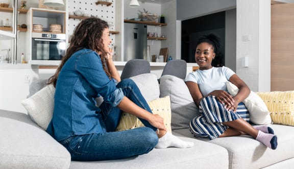 Two female roommates hanging out on couch.