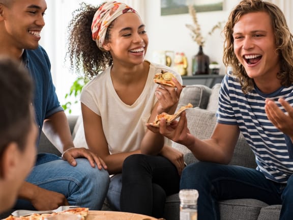 a group of people sitting on a couch laughing and eating pizza at Birdie on Woodland Greens, Austin, Texas