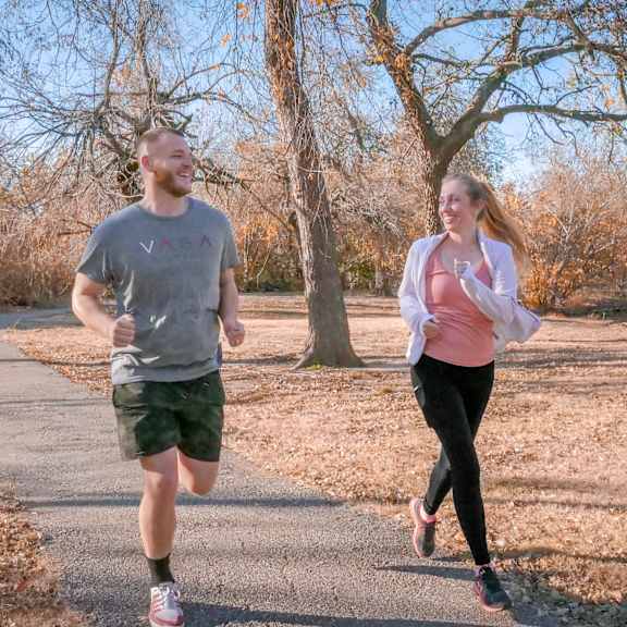 A man and a woman running down a road at Terrace on the Lake Apartment Homes.
