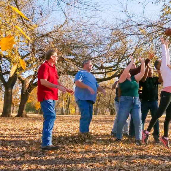a group of people playing with leaves on a tree