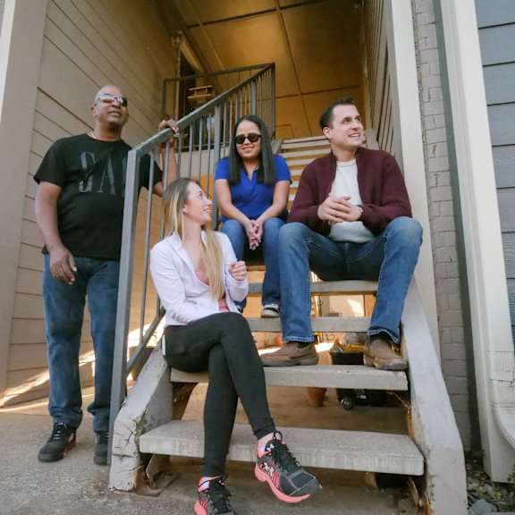 A group of people sitting on the steps of a house at Heritage Park