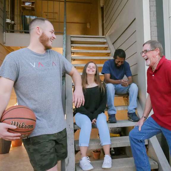 A group of people standing in a stairwell with a basketball at Yorkshire Apartments.