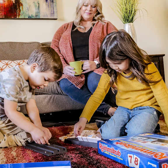 A mother watching two children play with toys in a living room at Camelback Pointe.