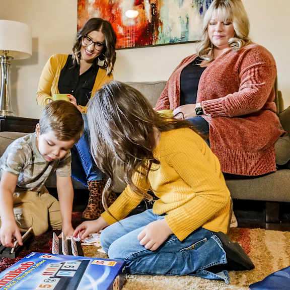 A family playing a board game in a living room at Manning Crossing Apartment Homes.