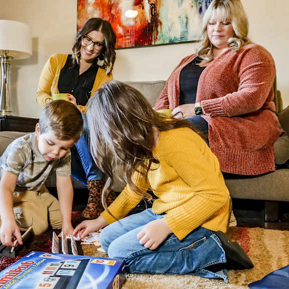A family playing a board game in a living room at Amber Ridge Apartment Homes.