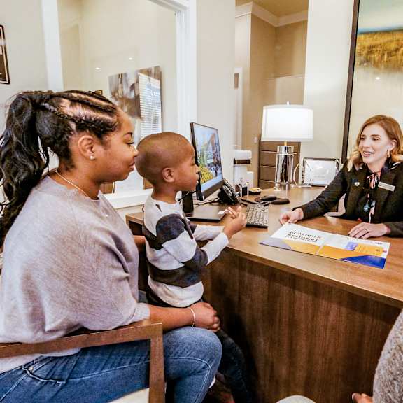 A woman sitting at a desk talking to a family at a reception desk at Westhaven Estates Apartment Homes.