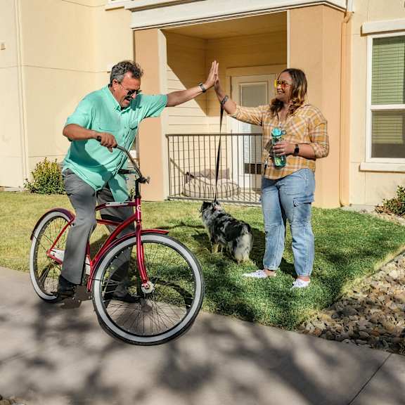 A couple giving each other a high five while riding a bike at Continental Apartment Homes.