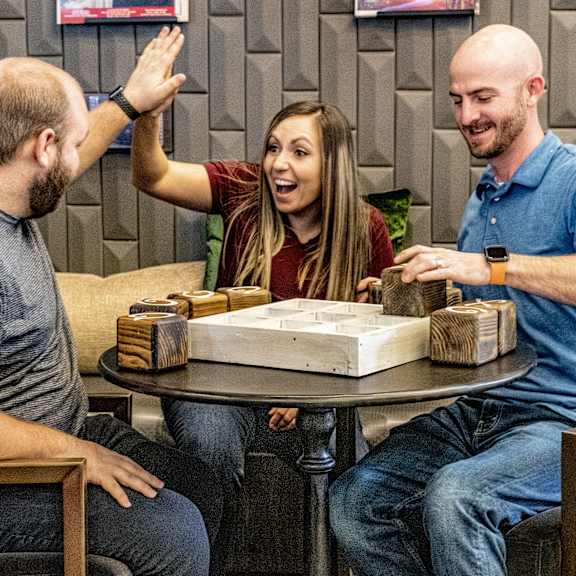 A group of people sitting around a table playing a board game at the Greenbriar.