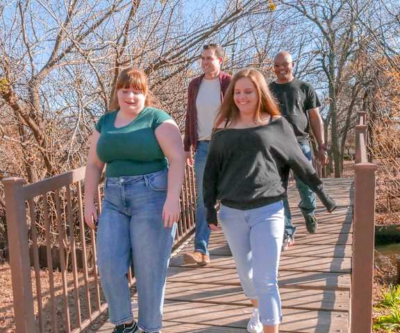 A group of people walking across a bridge at Brighton Park.