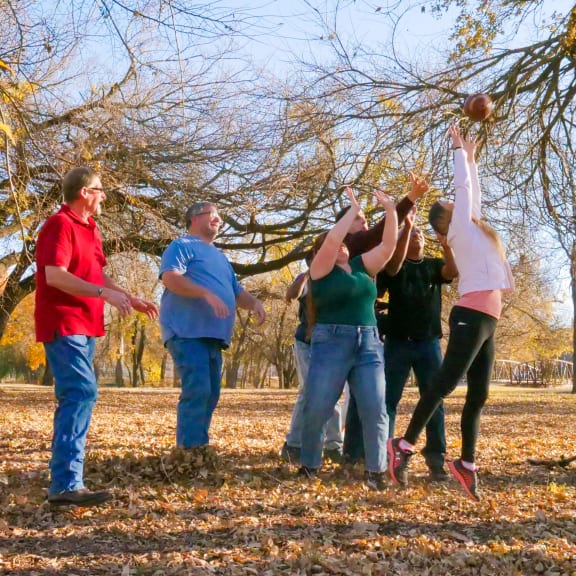 a group of people playing with leaves on a tree
