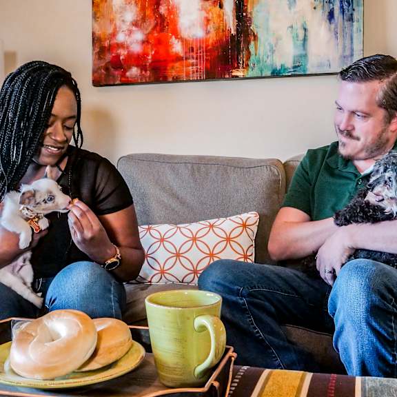 a man and woman sitting on a couch with two dogs