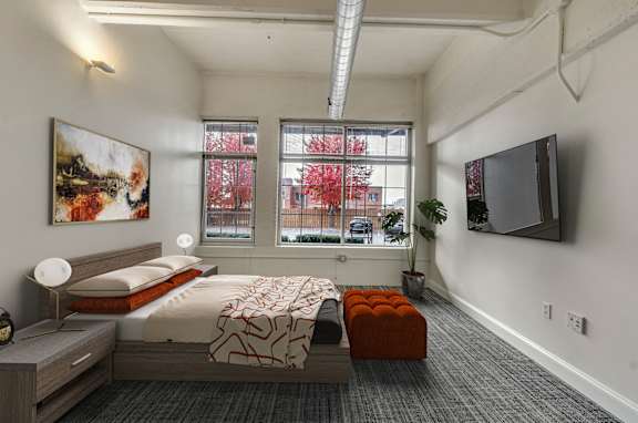 A bedroom with a bed, nightstand, and a painting on the wall.