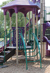 A playground with a purple slide and climbing wall.