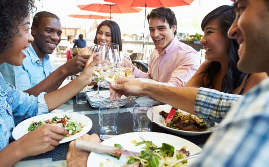 a group of people eating and drinking wine at a table