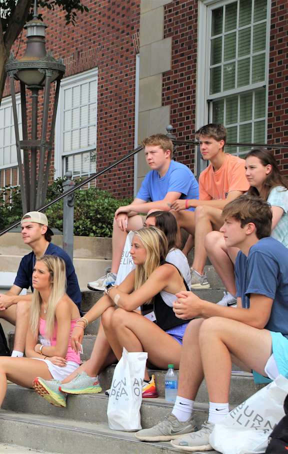 A group of people are sitting on the steps outside a building.