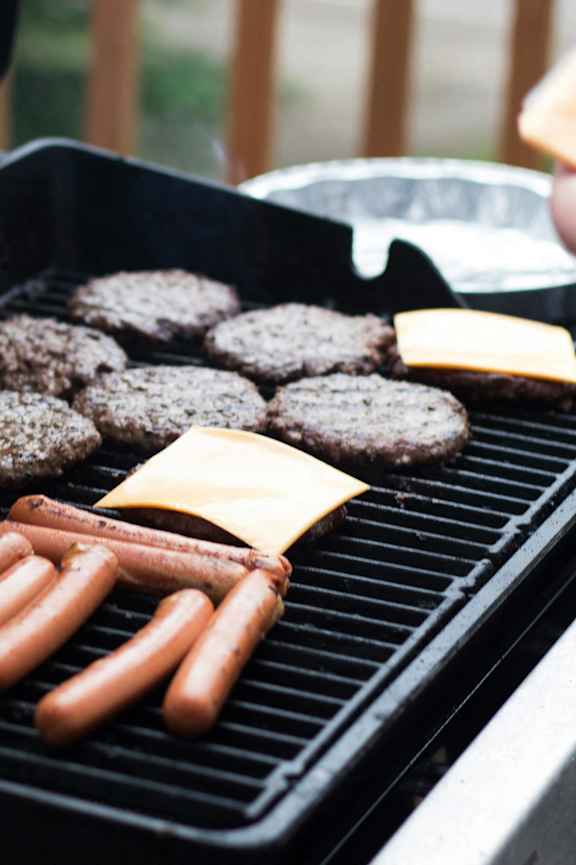 A person is grilling hamburgers and hot dogs.