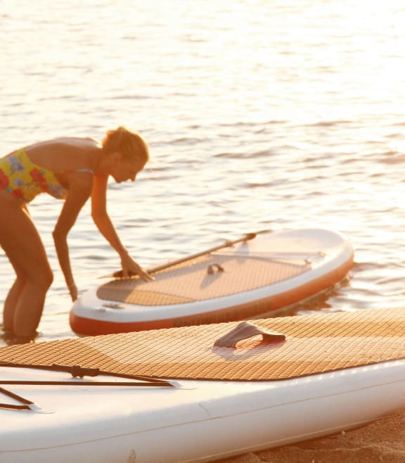 a woman standing on the beach with her surfboard