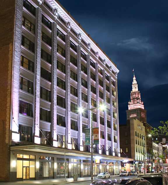 A tall building with a clock tower in the background at night.