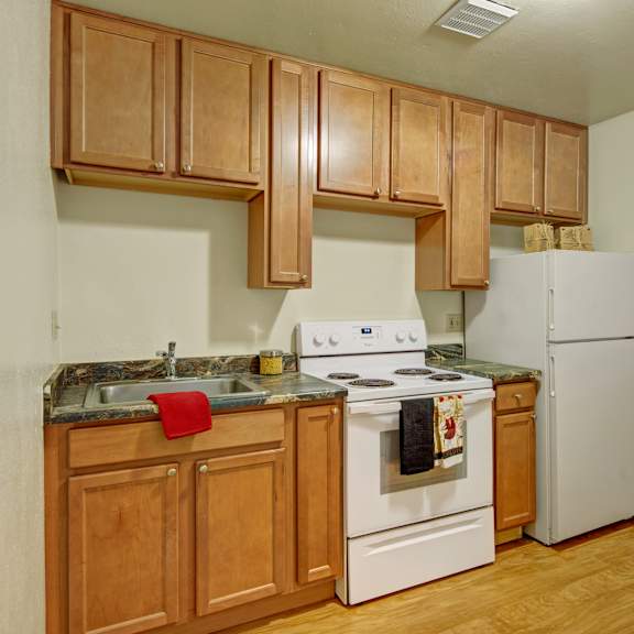 A kitchen with white appliances and marble counters at Conifer Grove. 