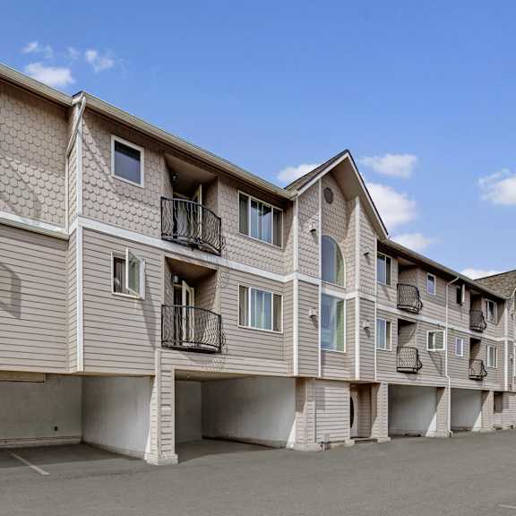 A view of the parking lot, garages, and the balconies and exterior of La Maisonette Apartments. 