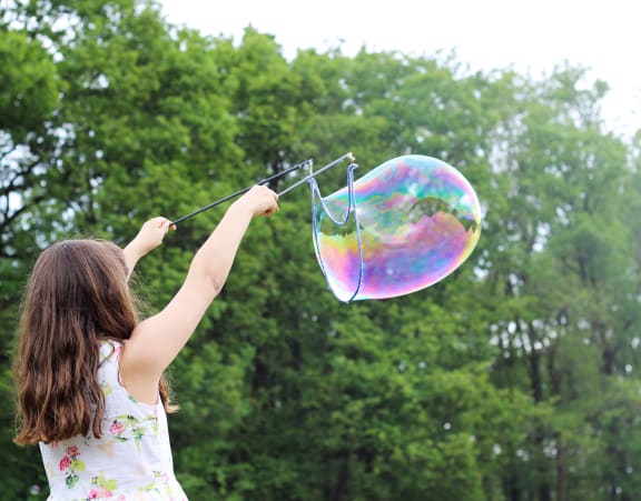 a young girl flying a kite in a forest