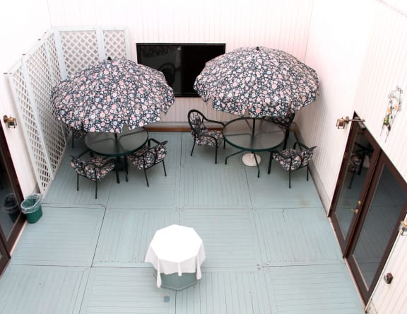 a patio with tables and umbrellas in a courtyard