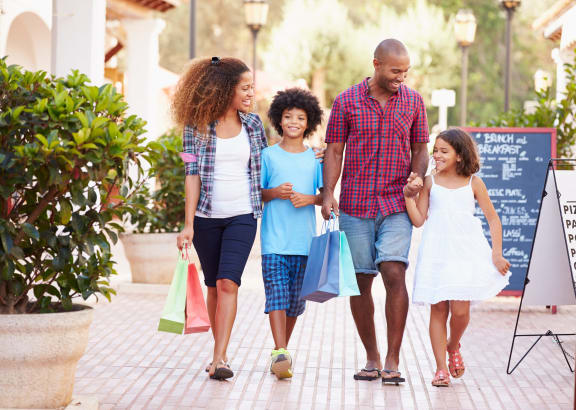 a family walking down the street with shopping bags at Castlewood Apartments, Clute, TX, 77531