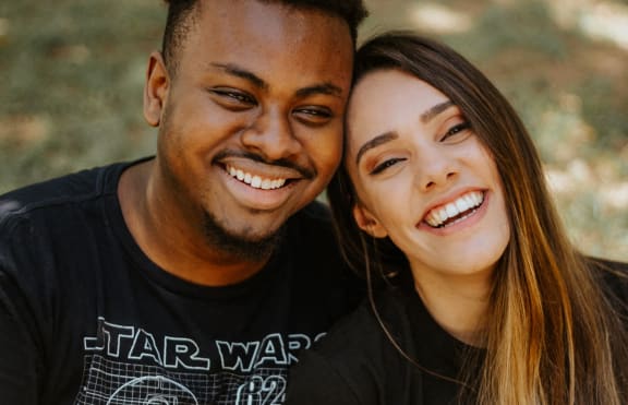 a man and a woman smiling with their arms around each other