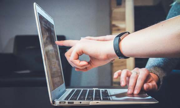 A person is using a laptop with their right hand on the trackpad and their left hand on the keyboard.