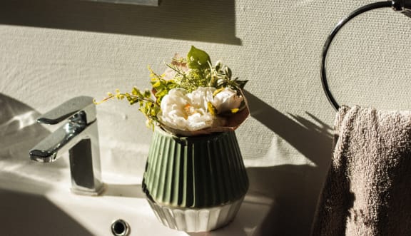 a vase filled with flowers sitting on a bathroom sink at Telka Apartments, Silverdale, WA, 98383