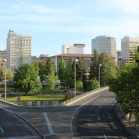 A city street with buildings in the background and a roundabout in the foreground.