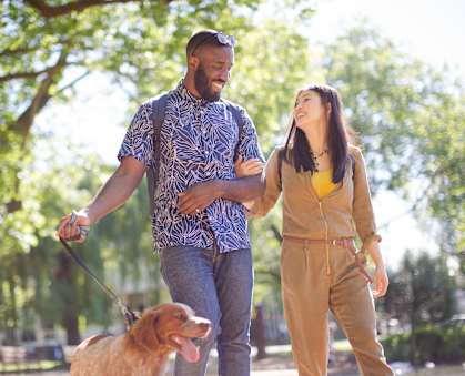 a couple walking their dog in the park