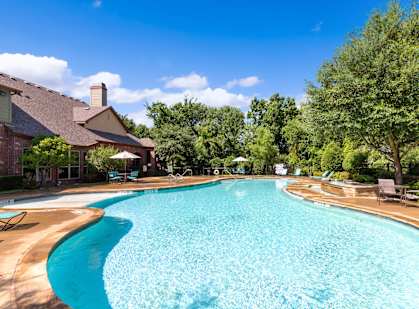 a swimming pool with trees and a house in the background