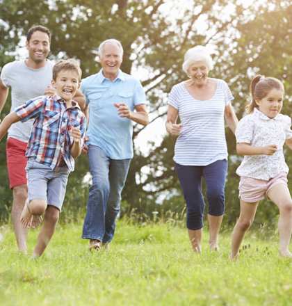 A family of five runs through a grassy field together.