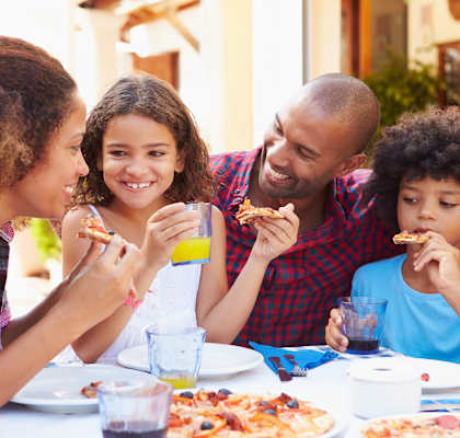 Four people eating pizza and drinking juice at a table.at Valencia Trace, ORLANDO Florida