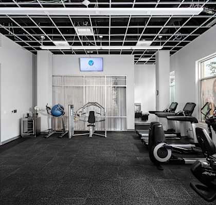 a gym with cardio equipment and a screen on the wall at The Residences of Wilmette, Wilmette, Illinois