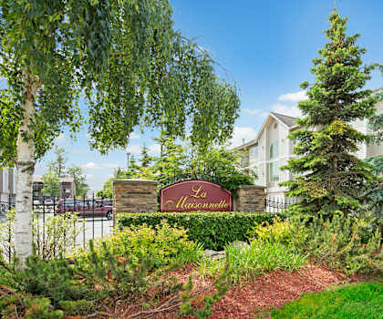 The exterior sign and building surrounded by greenery and trees of La Maisonette Apartments.