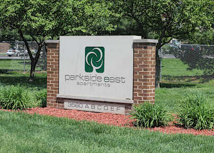A sign for Parkside East Apartments stands in front of a brick wall.
