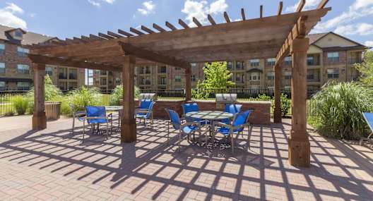 a patio with a table and chairs under a wooden pergola