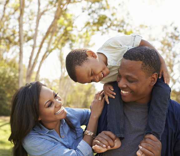 a man and woman laughing with a child on their shoulders at Windsor Crossing, Suitland Maryland