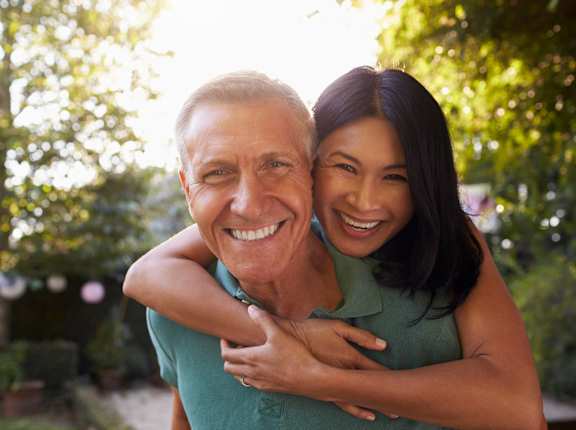 A man and woman hugging each other in a sunny outdoor setting.