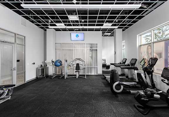 a gym with cardio equipment and a screen on the wall at The Residences of Wilmette, Wilmette, Illinois