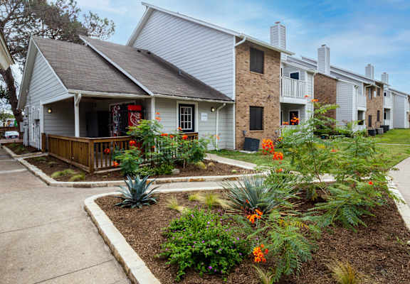 the front yard of a house with flowers and a sidewalk