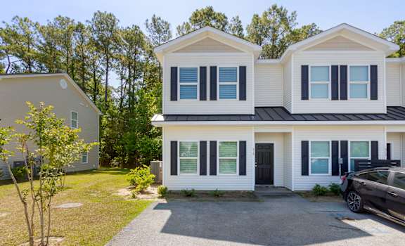 the front of the house with a car in the driveway and trees in the background at Waverly Place, North Charleston, SC, 29418