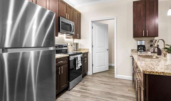 A kitchen with a stainless steel refrigerator and wooden cabinets.