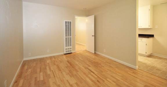 an empty living room with wood flooring and an open door