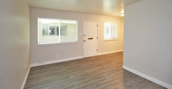 an empty living room with wood flooring and a white door