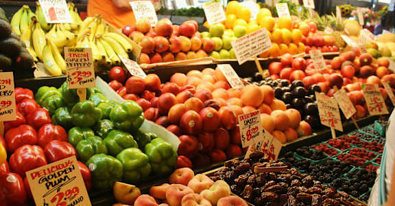 A fruit stand with a variety of fruits including bananas, apples, and peaches.