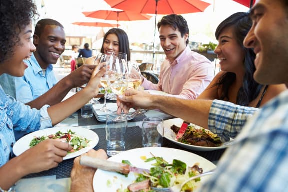 a group of people eating and drinking wine at a table